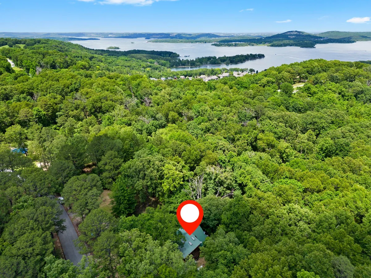 A sweeping view of lush greenery, a distant water body, and rolling scenic hills. The vantage point suggests tranquility and the vastness of the surrounding landscape, inviting guests to hike, boat, or simply soak in the serenity. The image captures the essence of the outdoor adventures available nearby, like hiking at Dogwood Canyon or boating on Table Rock Lake.
