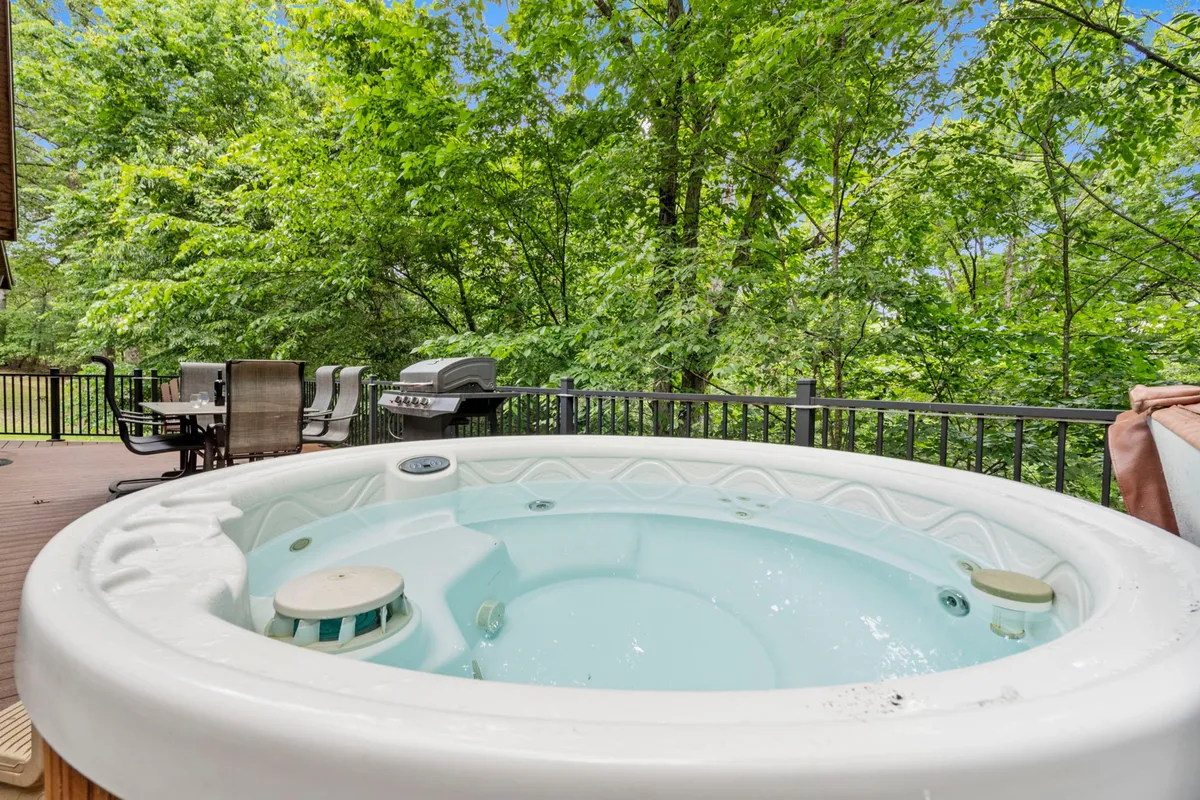 An outdoor living area featuring a hot tub nestled amongst greenery with an adjacent seating area. The space feels secluded and tranquil, ideal for either peaceful morning coffee or lively evening barbecues under the stars.