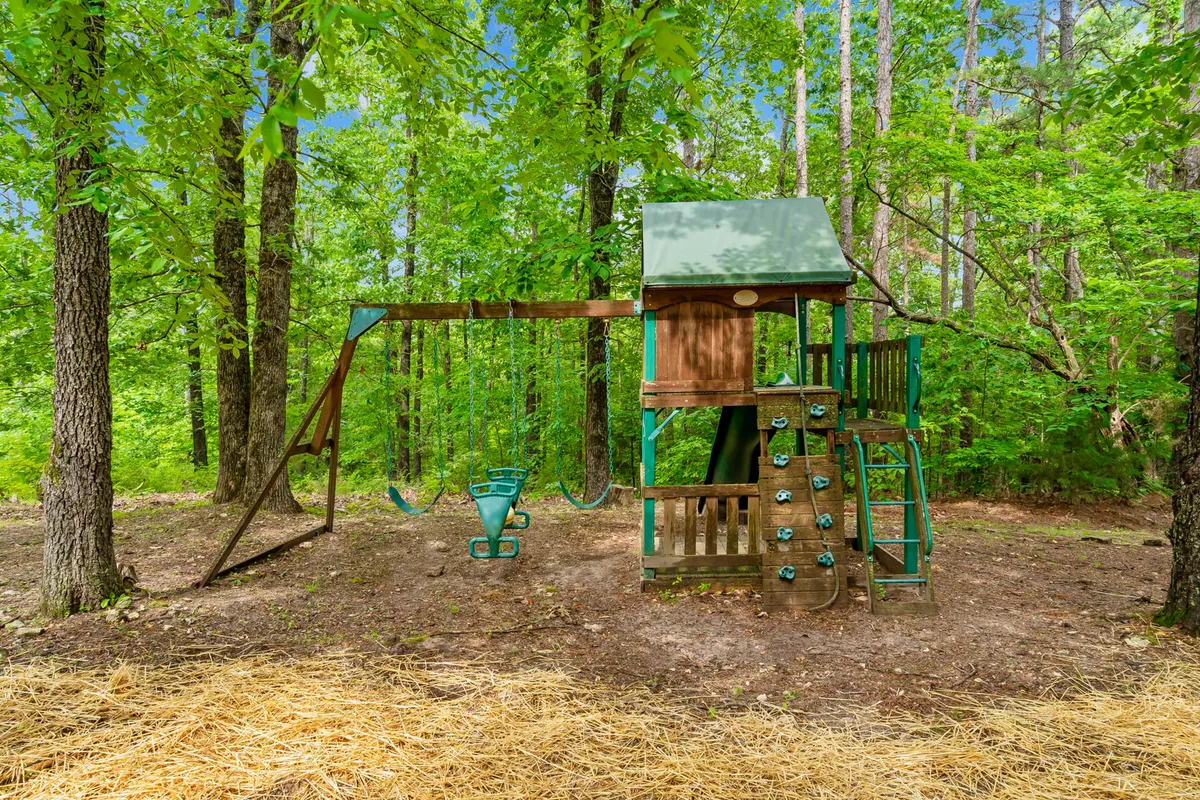 A joyful outdoor playground scene with a swing set, climbing wall, and open space for children to play. The area is designed for family fun and community gatherings, reinforcing the exclusive, family-friendly nature of the estate.