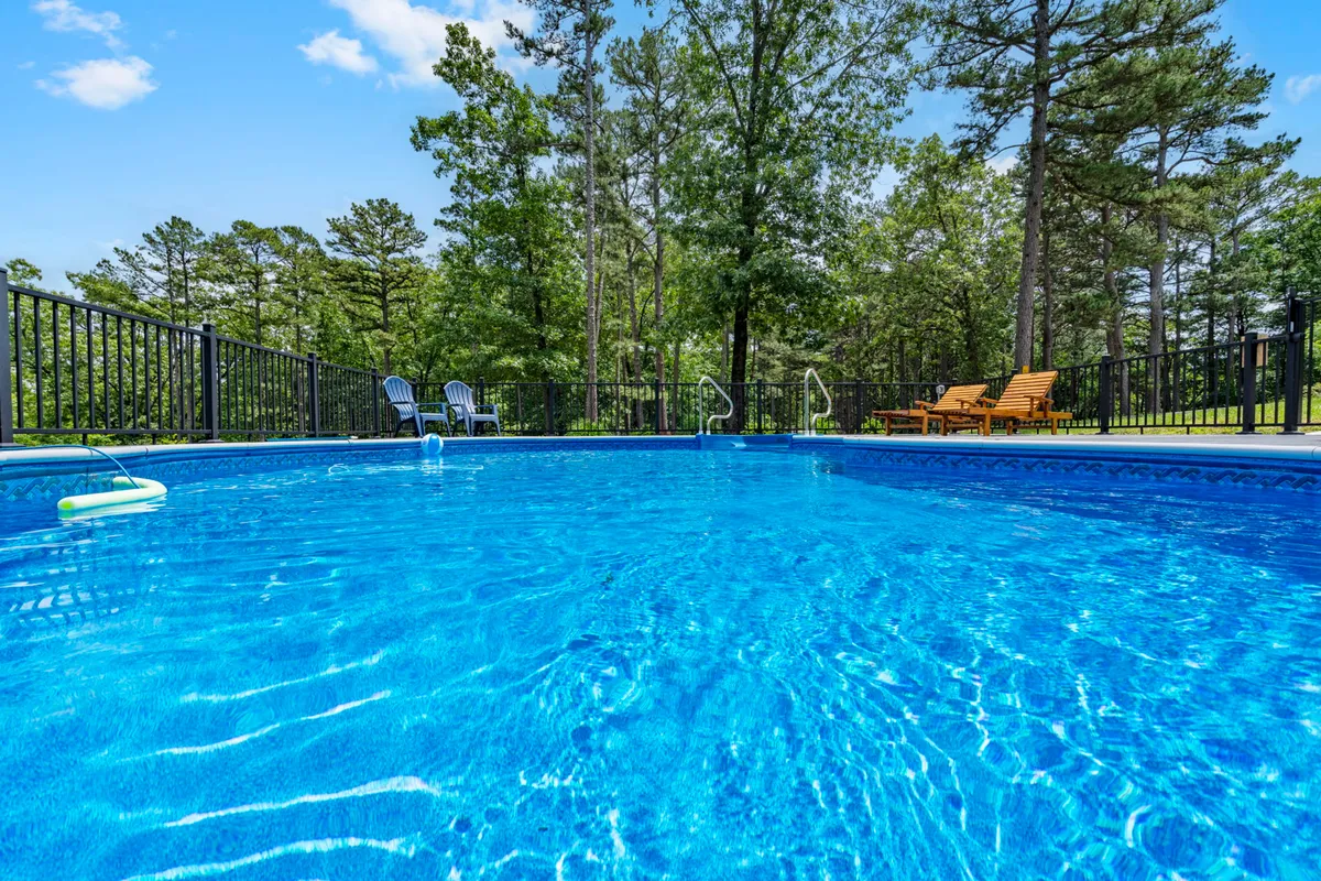 A tranquil pool setting with lounge chairs shaded by surrounding trees. The space feels calm and inviting, offering opportunities for both group activities and peaceful moments. The setup is perfect for gatherings, sunbathing, or simply unwinding together.