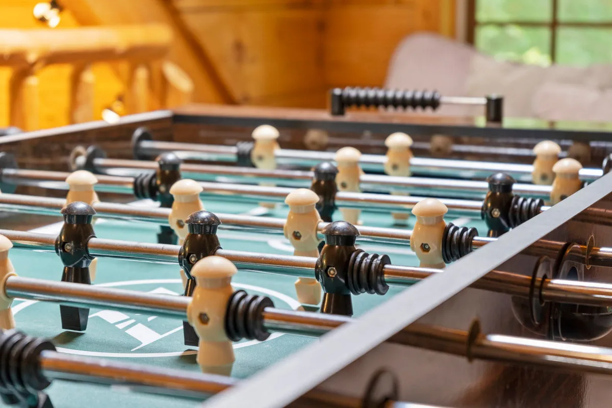 A close-up of a foosball table with vibrant game pieces atop a green felt surface, conveying the excitement of gameplay and the lively atmosphere of family gatherings.